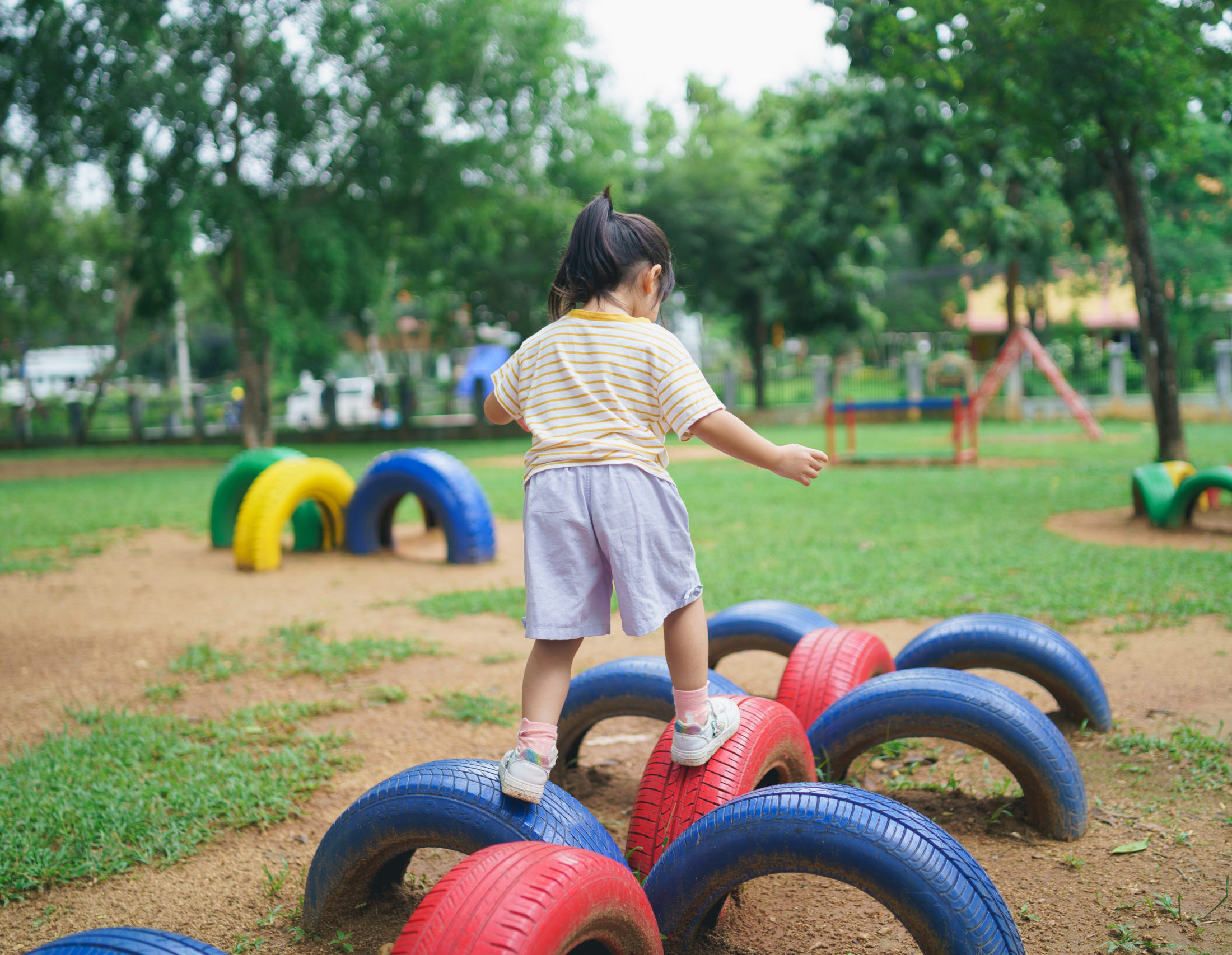Cute asian girl smile play on school or kindergarten yard or playground. Healthy summer activity for children. Little asian girl climbing outdoors at playground. Child playing on outdoor playground.